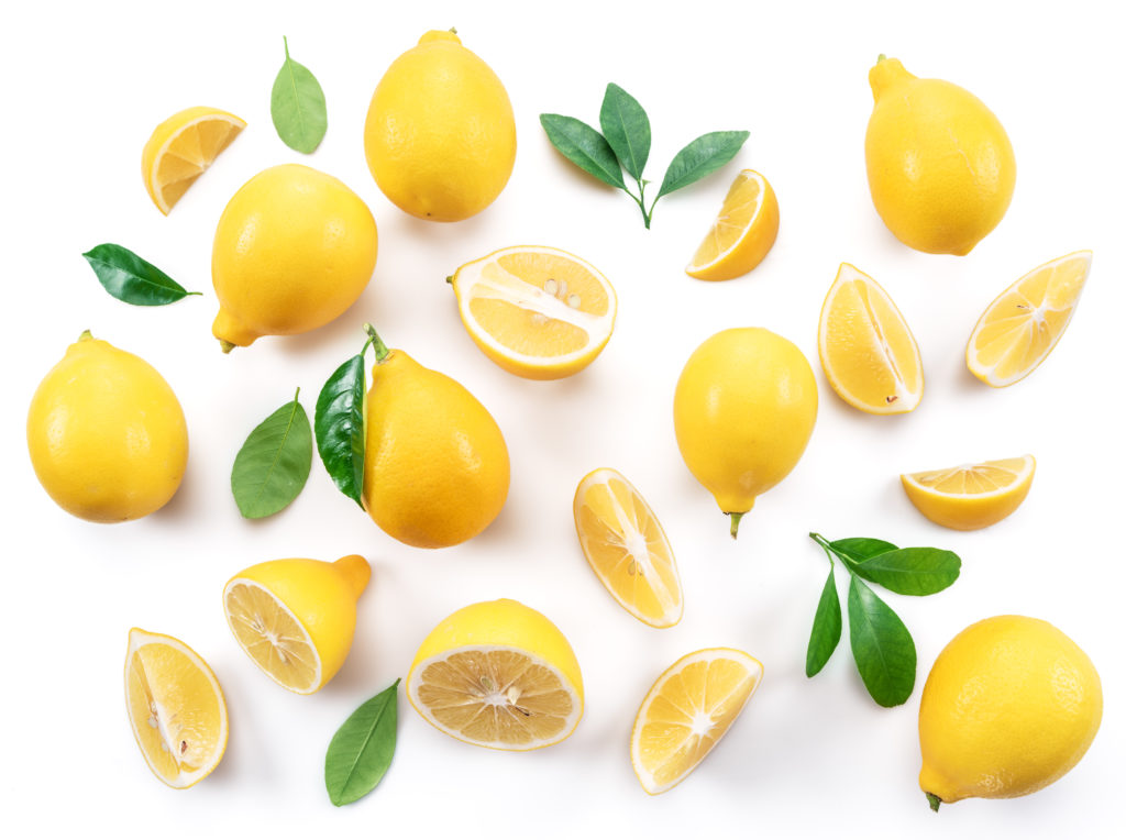 Ripe lemons and lemon leaves on white background. Top view.